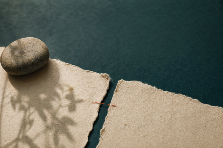 Hands mending a torn paper with thread, representing repairing a small rupture
